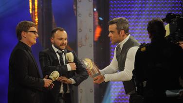 Laudator Robbie Williams überreicht den Preis an Christian Bollert und Marcus Engert (detektor.fm). © Sebastian Gerhard 