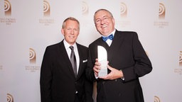 Werner Reinke (hr1), Preisträger in der Kategorie "Bester Moderator", posiert mit Laudator Johannes B. Kerner vor einer Fotowand im Schuppen 52 in Hamburg. © NDR 