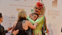 Radiopreis-Laudator Robbie Williams in den Armen von Olivia Jones auf dem Roten Teppich. © Marco Maas