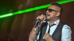 Sean Paul singt in ein Mikrofon bei der Radiopreisgala 2013. Am Kragen hat er einen Lippenstift-Abdruck. © fotografirma Foto: fotografirma