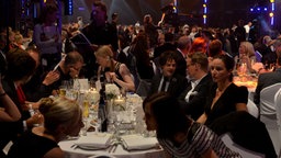 Jamie Cullum und seine Begleiter verfolgen an ihrem Tisch die Gala © NDR Foto: fotografirma