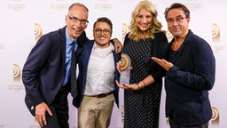 Laudator Jan Josef Liefers (r.) hat den Preis für die "Beste Morgensendung" an John Ment (l.), André Kuhnert und Birgit Hahn von Radio Hamburg überreicht. © Deutscher Radiopreis/Moris Mac Matzen Foto: Moris Mac Matzen