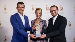 Die Gewinner des Deutschen Radiopreises in der Kategorie "Beste Reportage": Benedikt Strunz und Philipp Eckstein von NDR Info mit Laudatorin Julia Becker. © Deutscher Radiopreis / Morris Mac Matzen Foto: Morris Mac Matzen