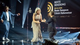 Beate Sampson und Ulrich Habersetzer gewinnen den Radiopreis in der Kategorie "Beste Sendung". Mathias Mester übergibt den Preis. © Deutscher Radiopreis / Benjamin Hüllenkremer Foto: Benjamin Hüllenkremer