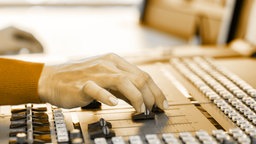 Eine Hand schiebt die Regler an einem Mischpult © Fotolia Foto: Kzenon