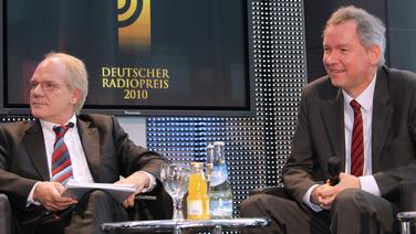 Lutz Kuckuck und Lutz Marmor in Sesseln um einen kleinen Tisch mit Getränken sitzend. Im Hintergrund ein Bildschirm mit dem Logo des Deutschen Radiopreis 2010. © NDR Foto: Marcus Krüger