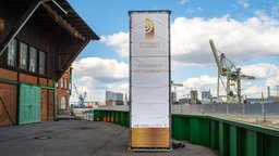 Blick vom Schuppen 52 in Richtung Elbphilharmonie, im Vordergrund ein Plakat des Deutschen Radiopreises © NDR Foto: Janine Kühl